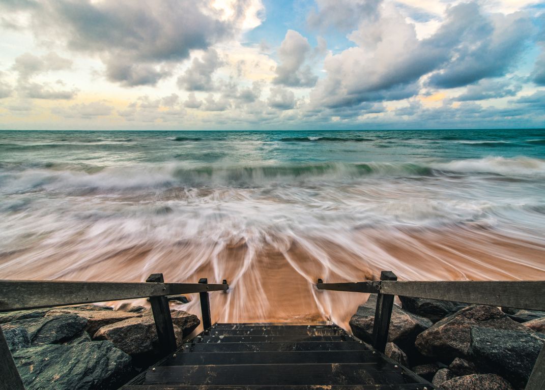 Ocean waters rush to a staircase that leads the way to welcoming seas.