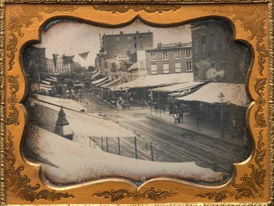 Shade-protecting overhangs known as awnings line a street in New York City in the 1850s.