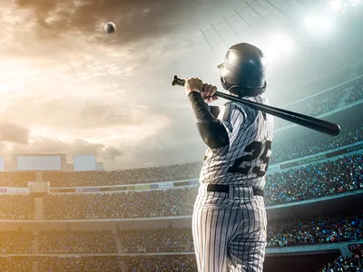 A baseball player hits a ball while at bat in a crowded stadium