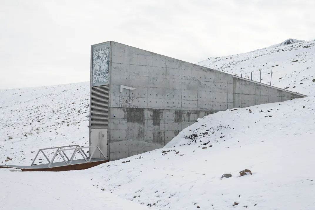 a narrow gray building built into the side of a snow-covered hill