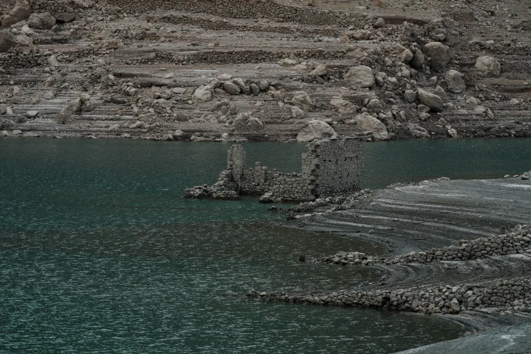 fragments of a building's stone walls stand up from the water which appears to have dropped in depth