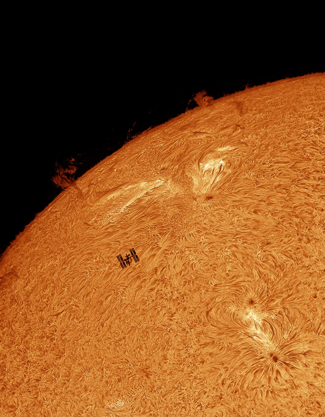 An image of the surface of the sun with the International Space Station traversing in front of it.